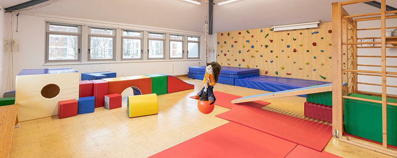 Kindergarten-Turnhalle mit Kletterwand und bunten Matten