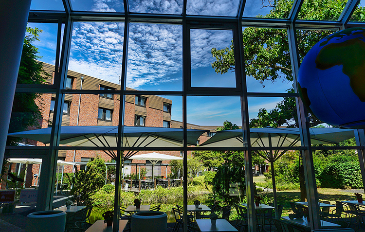 Blick durch eine große Glasfront auf einen begrünten Hotel-Innenhof
