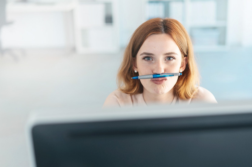Frau hält einen Stift zwischen Nase und Lippen
