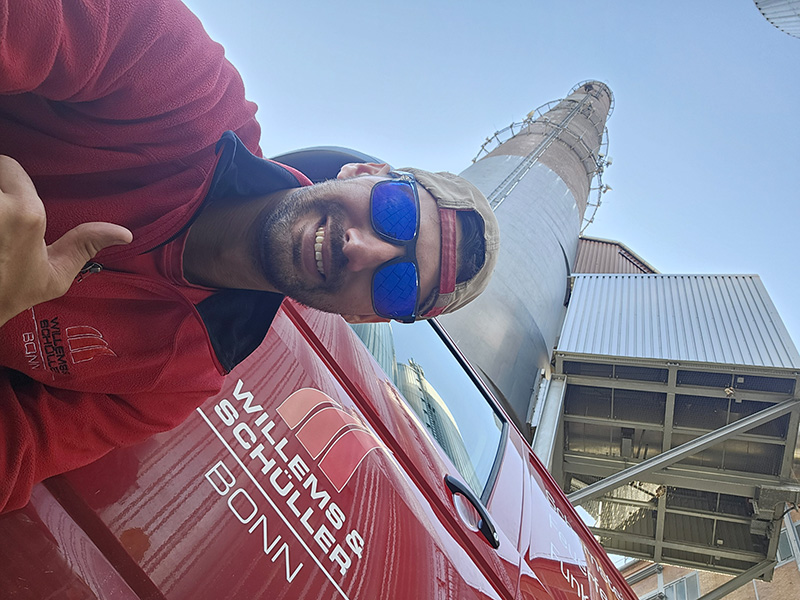 Mann neben einem Industrieschornstein