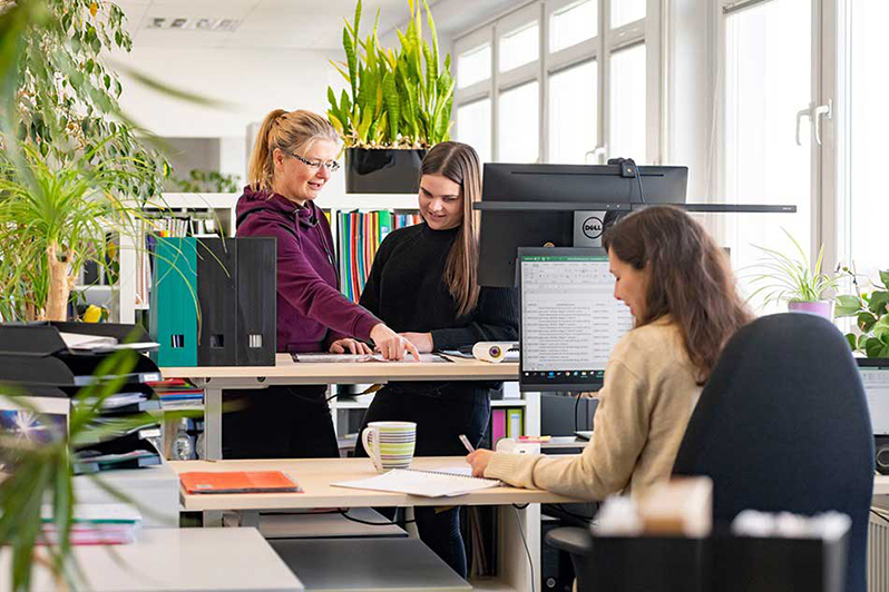 Drei Personen arbeiten in einem hellen Büro