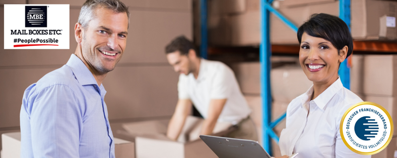 Mail Boxes – Mitarbeiter in einem Lager lächeln in die Kamera.
