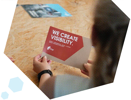 Hände halten Karte mit der Aufschrift WE CREATE VISIBILITY