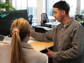 Zwei Kollegen betrachten gemeinsam einen Monitor am Arbeitsplatz