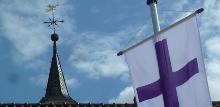 Kirchturmspitze mit Fahne und Wetterfahne