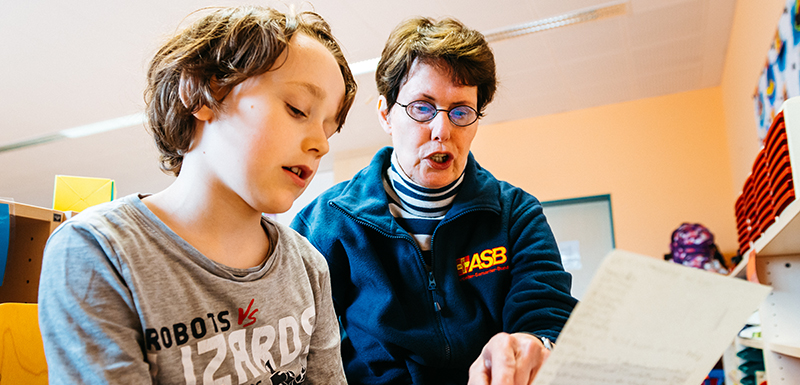 Kind und Erwachsene lesen zusammen.