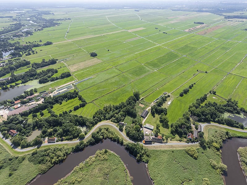 Luftbild einer flachen Agrarlandschaft mit Feldern, Gräben und Flusswindung