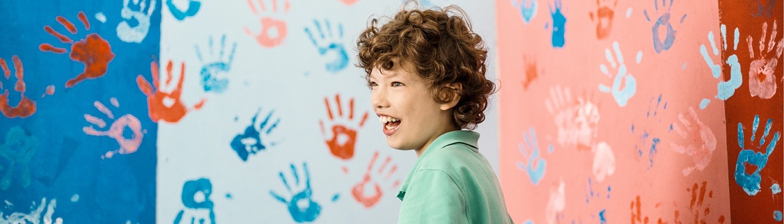 Kind vor einer Wand voller Handabdrücke