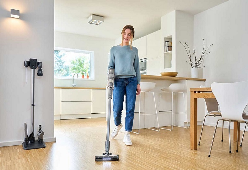 Frau staubsaugt moderne Küche