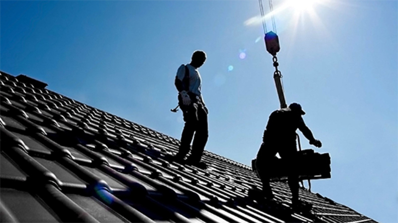 Zwei Arbeiter arbeiten auf dem Dach