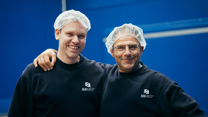 Team in Produktionshalle mit Hygienekleidung