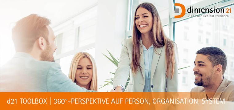 Ein Mann schüttelt einer Frau die Hand. Eine weitere Frau und ein weiterer Mann sitzen zwischen den beiden an einem Tisch.