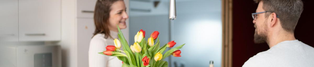 Paar in moderner Küche mit bunten Tulpen