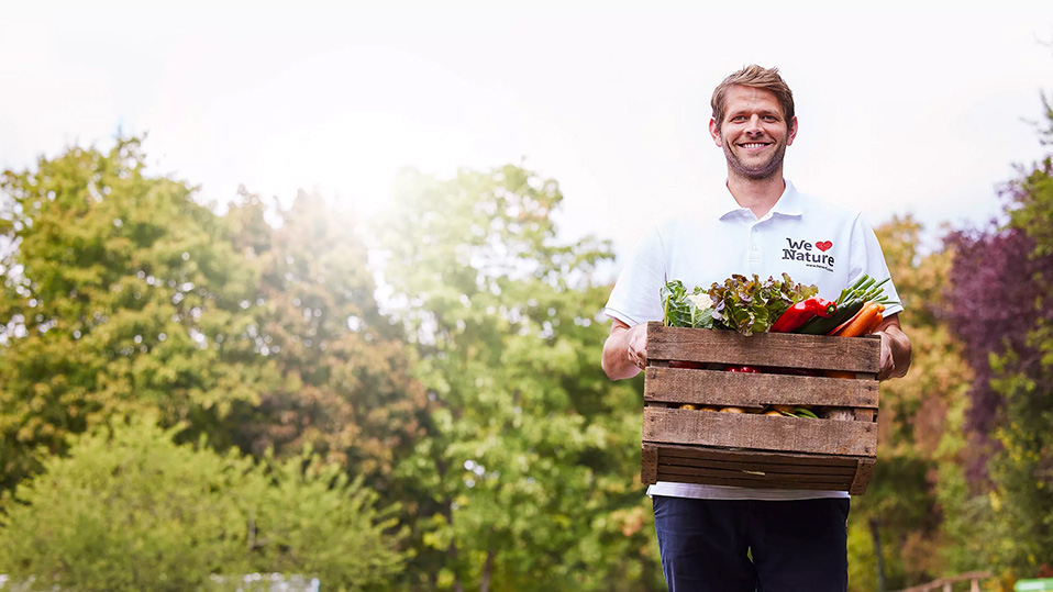Mann hält eine Kiste mit Gemüse