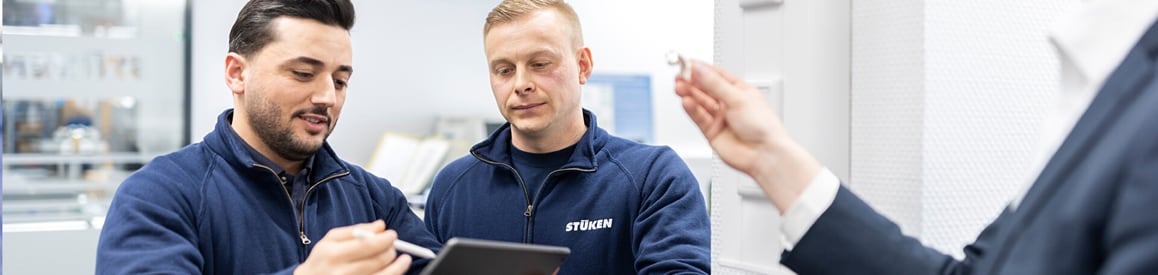 Zwei Stücken-Mitarbeiter betrachten Tablet und Kleinteil im Gespräch