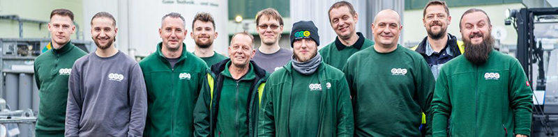 Mitarbeiter in grüner PGC-Arbeitskleidung stehen nebeneinander