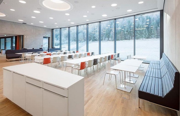 Raum mit vielen weißen Tischen und Stühlen 