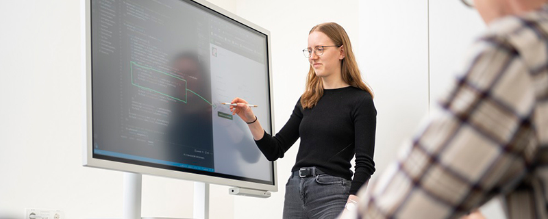 Frau erklärt Code am Touch-Monitor