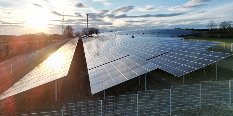 Nahaufnahme von Solarmodulen auf einer Freifläche bei tiefstehender Sonne