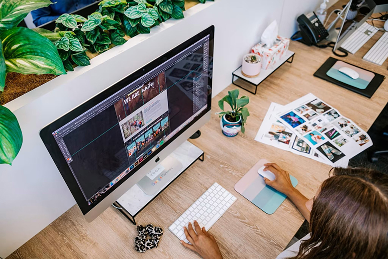 Designerin bearbeitet Website am iMac im Büro