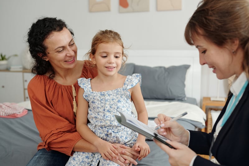 Frau und Kind im Beratungsgespräch mit einer Person, die Notizen macht