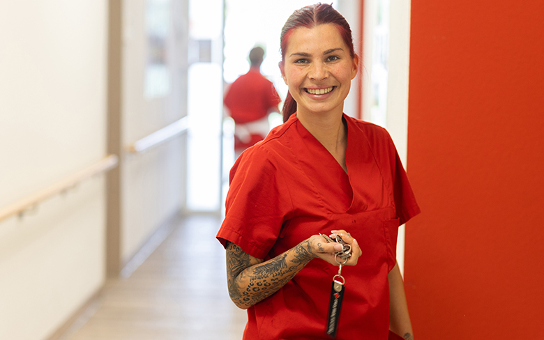 Pflegekraft in roter Dienstkleidung
