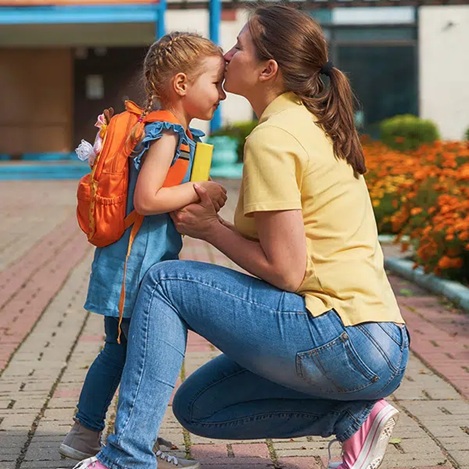 Mutter küsst Kind vor Schule