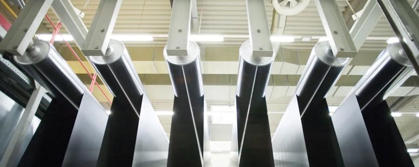 Schwarze Folienbahnen über Walzen in Industrieanlage