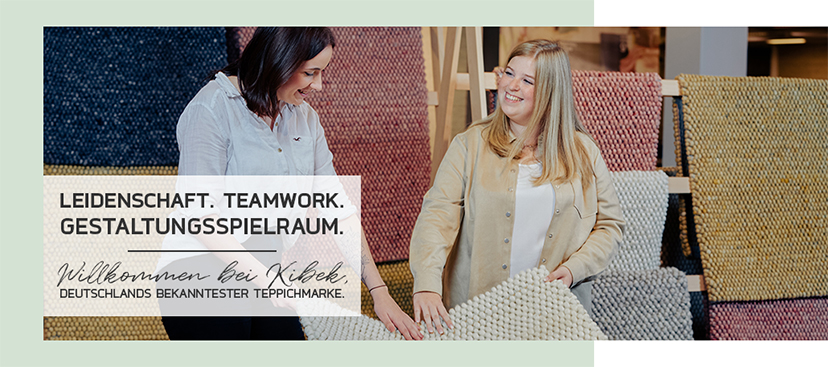 Zwei Frauen begutachten lächelnd Teppiche bei Kibek. - Leidenschaft. Teamwork. Gestaltungsspielraum. Willkommen bei Kibek, Deutschlands bekanntester Teppichmarke.