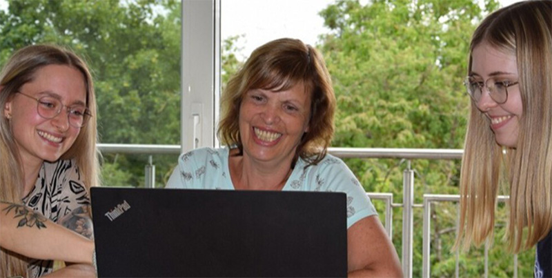 Drei Frauen schauen auf einen Laptop